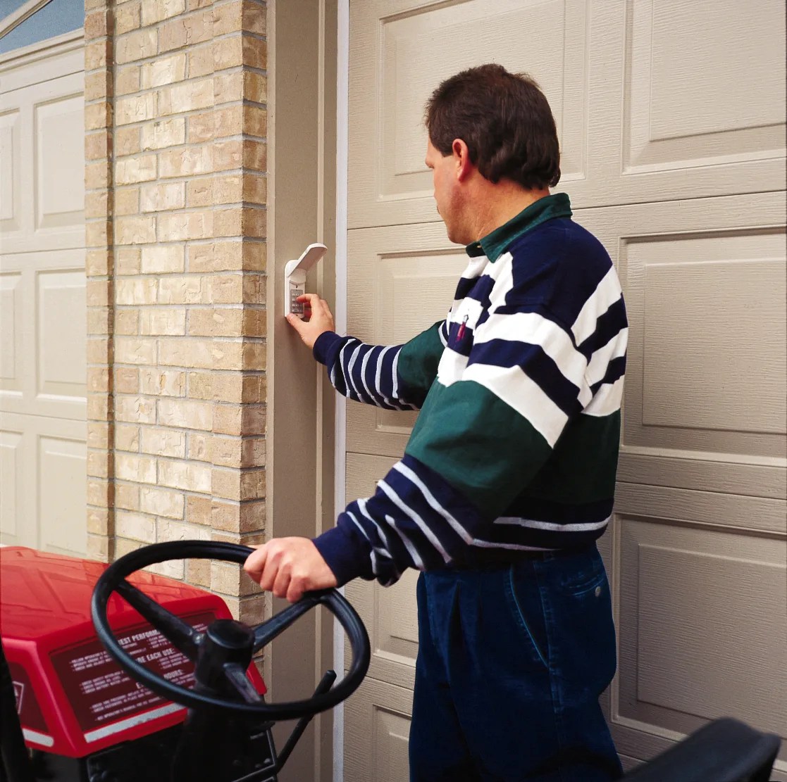 Garage door keypad mounted on exterior wall next to a garage door