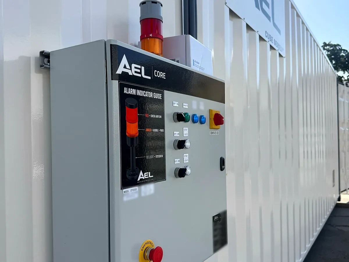 Exterior-mounted AEL CORE control panel on an AEL Cube Series container, with tower light, pilot lights, disconnect and emergency stop