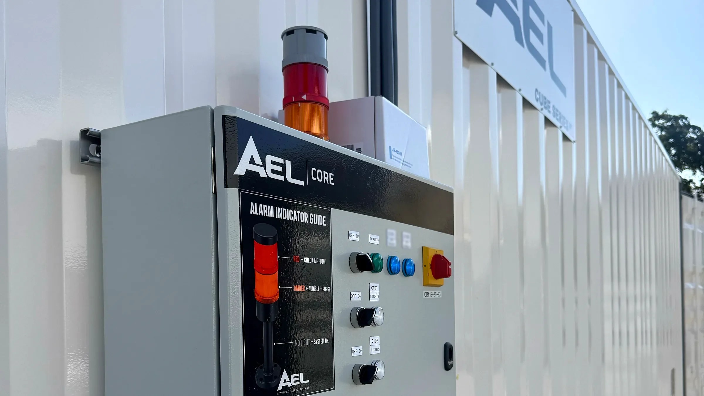 AEL CORE control panel with tower light and alarm indicator guide mounted on the exterior wall of a white AEL Cube Series container
