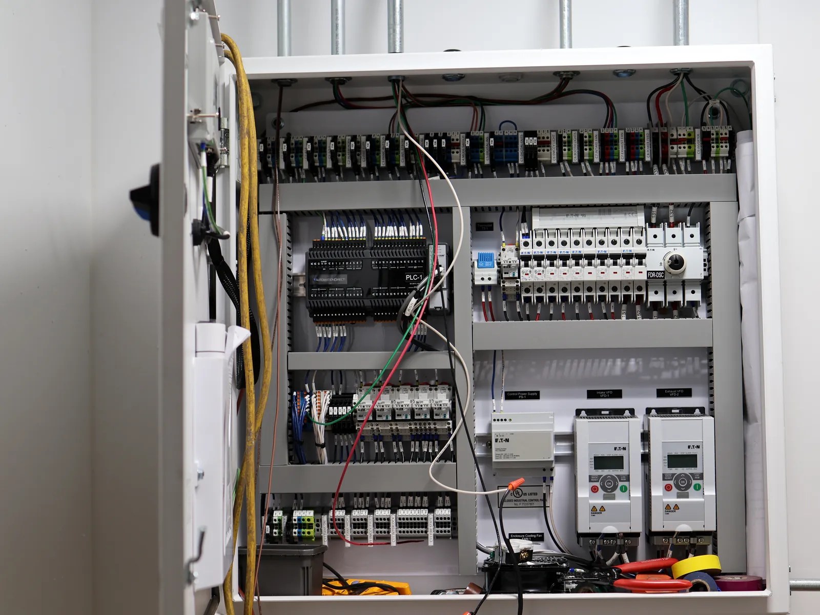 Open control panel showing neatly routed wiring, terminal blocks, breakers and motor drives