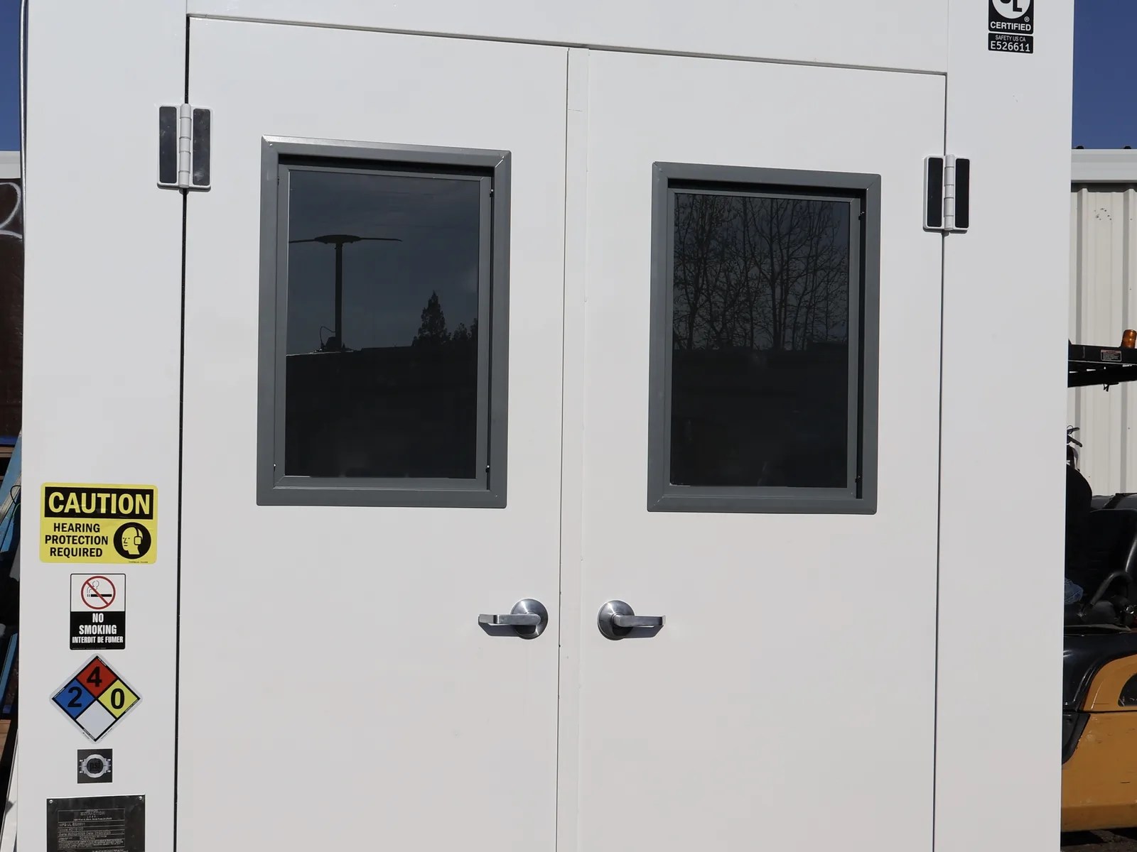 White double-door walk-in booth with vision windows, door closers and safety placards