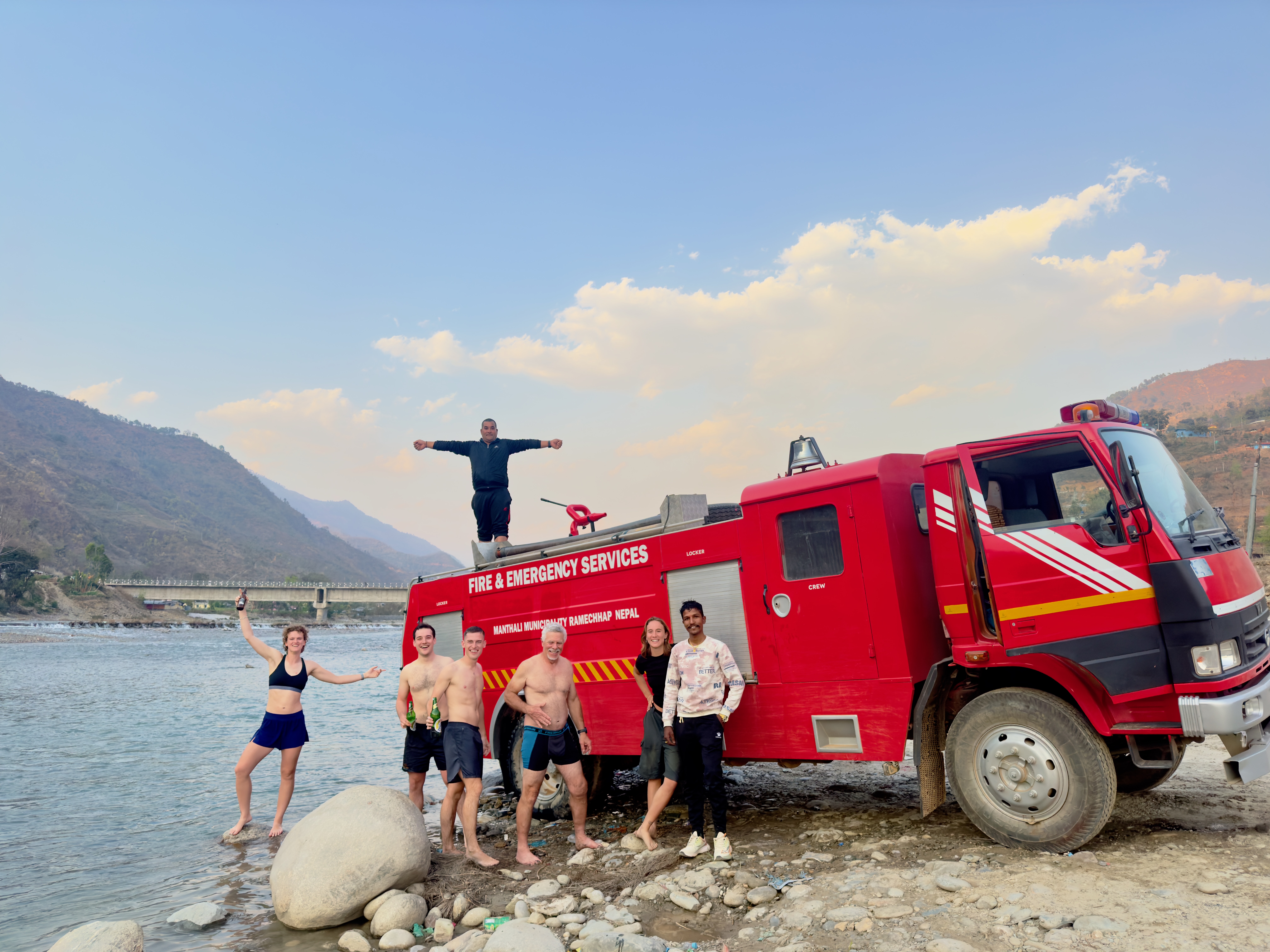 Friends enjoying some drinks at sunset on a fire truck in Nepal.