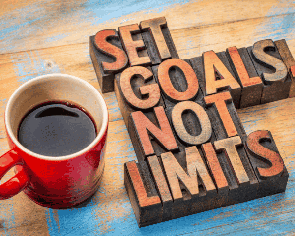 "Set goals not limits" sign next to a coffee mug.