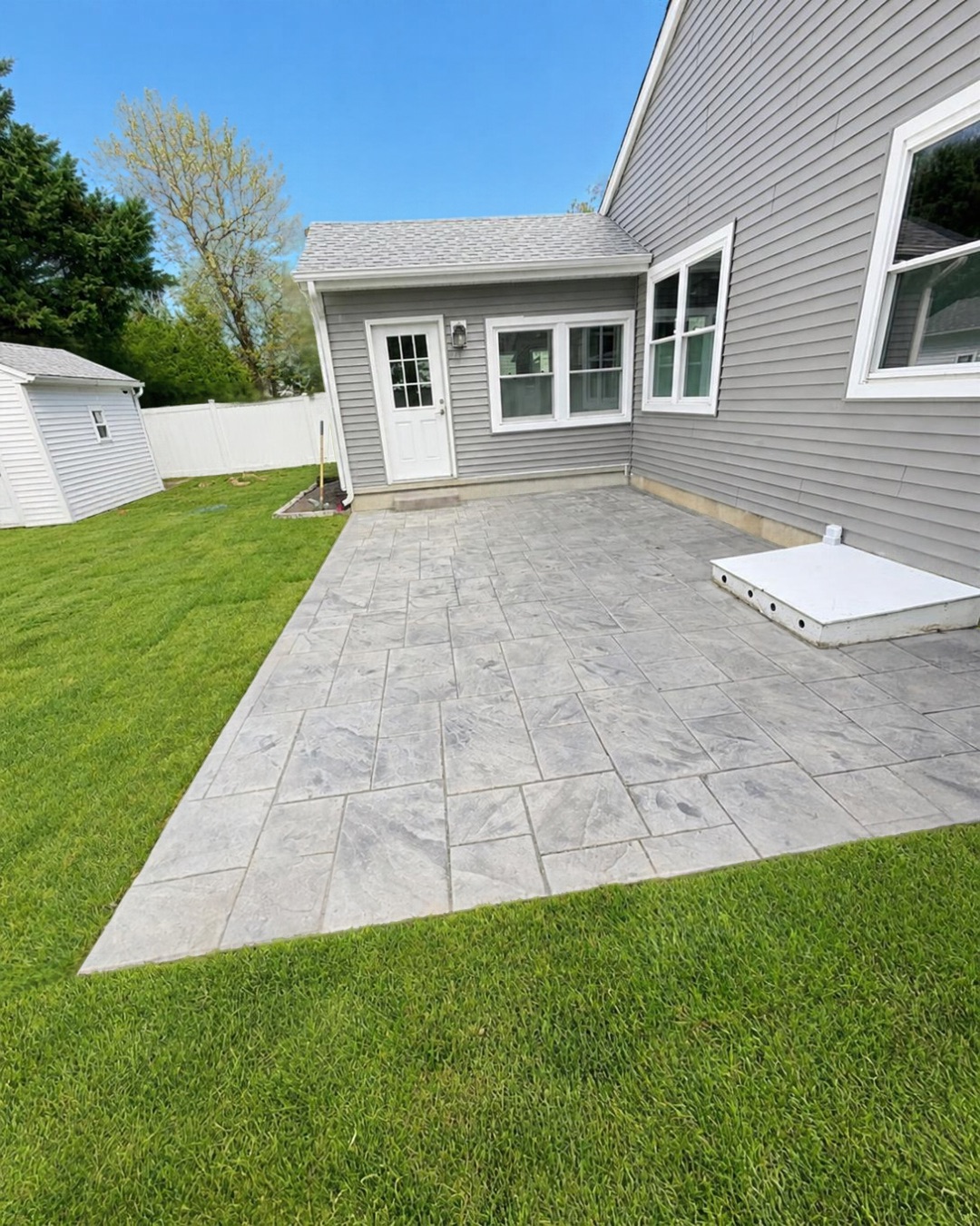 Complete yard redesign featuring a green sod lawn, paver patio, landscaped beds, and a new driveway by A&F Lawn Care.