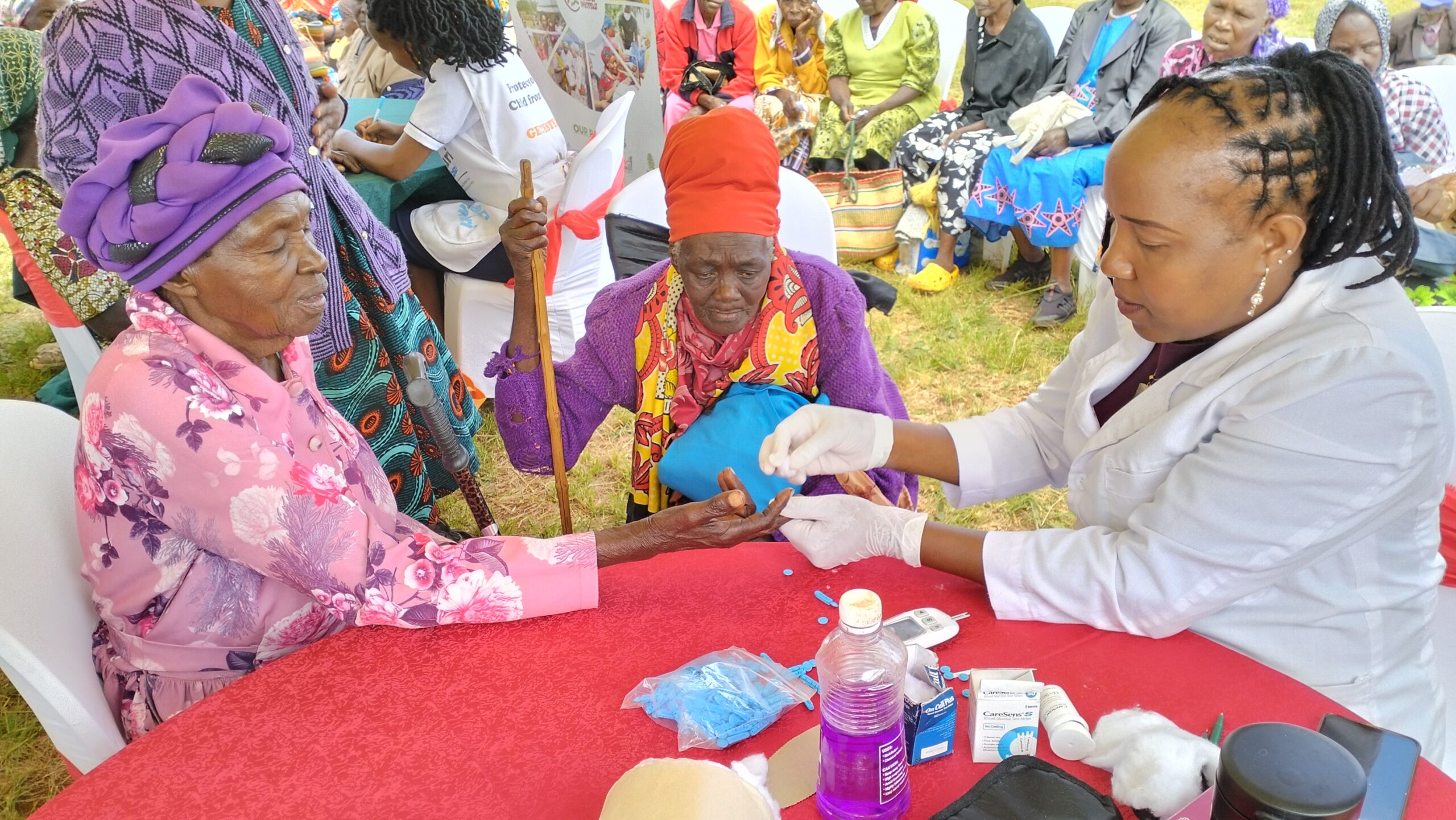 Two elderly women have their blood sugar and blood pressure tested at Kagunduini grounds,Kandara.