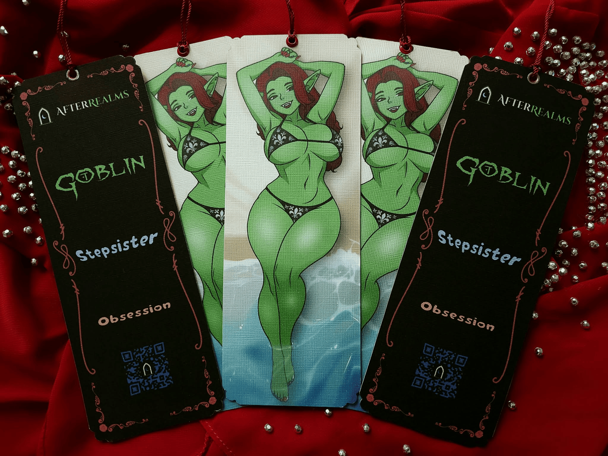 A spread of five bookmarks on a background of red. The bookmarks feature an appealing green skinned woman in a teeny bikini on one side and a black-and-red filigree on the other, surrounding the works AfterRealms, and Goblin Stepsister Obsesssion. There is also a QR code.