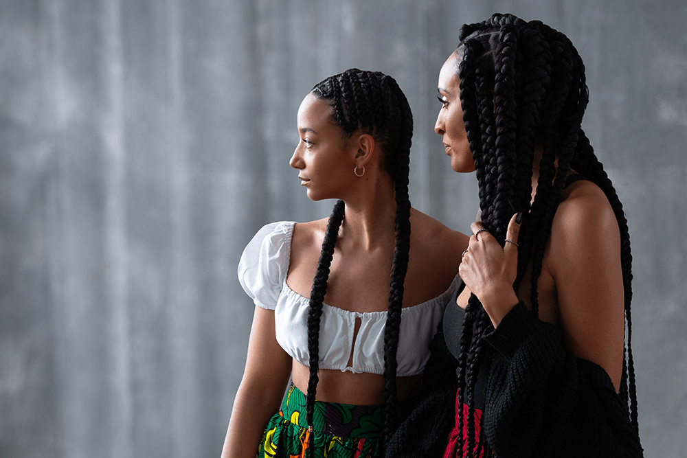 zwei Afrikanische Frauen mit langen geflochtenen Zöpfen in traditioneller afrikanischer Kleidung