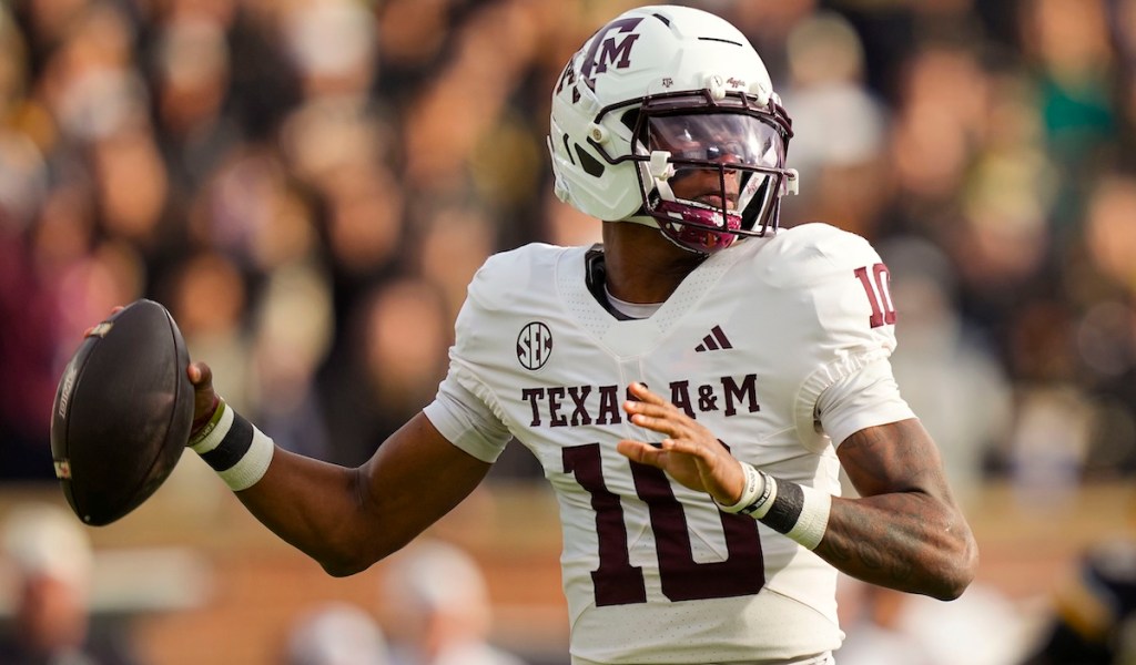 Texas A&M football player wearing a white jersey with the number 10, preparing to throw a football on the field.