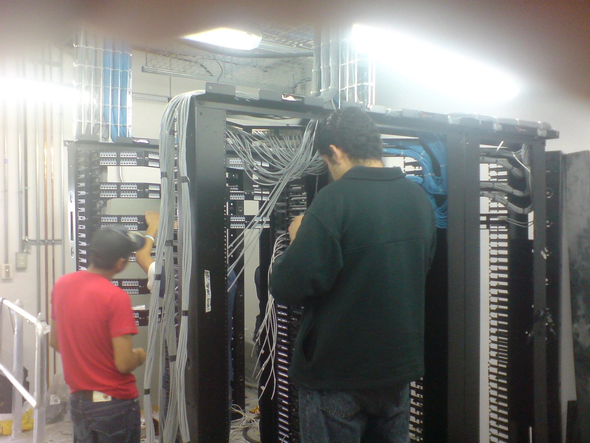 Des techniciens en train de réorganiser un local d'infrastructure informatique