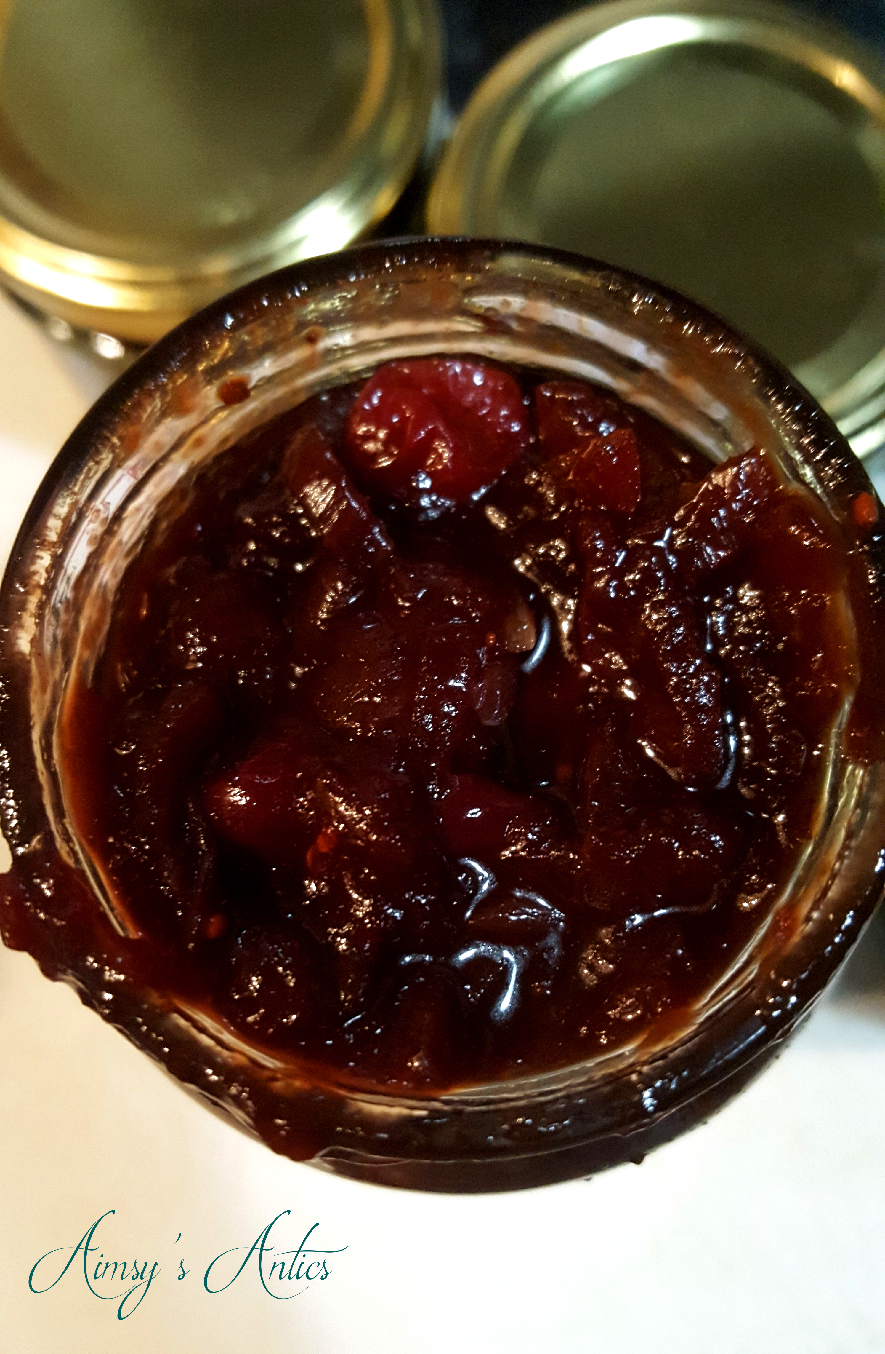 Image of the top of an open jar of the cranberry and red onion relish. Gold lids in the background.