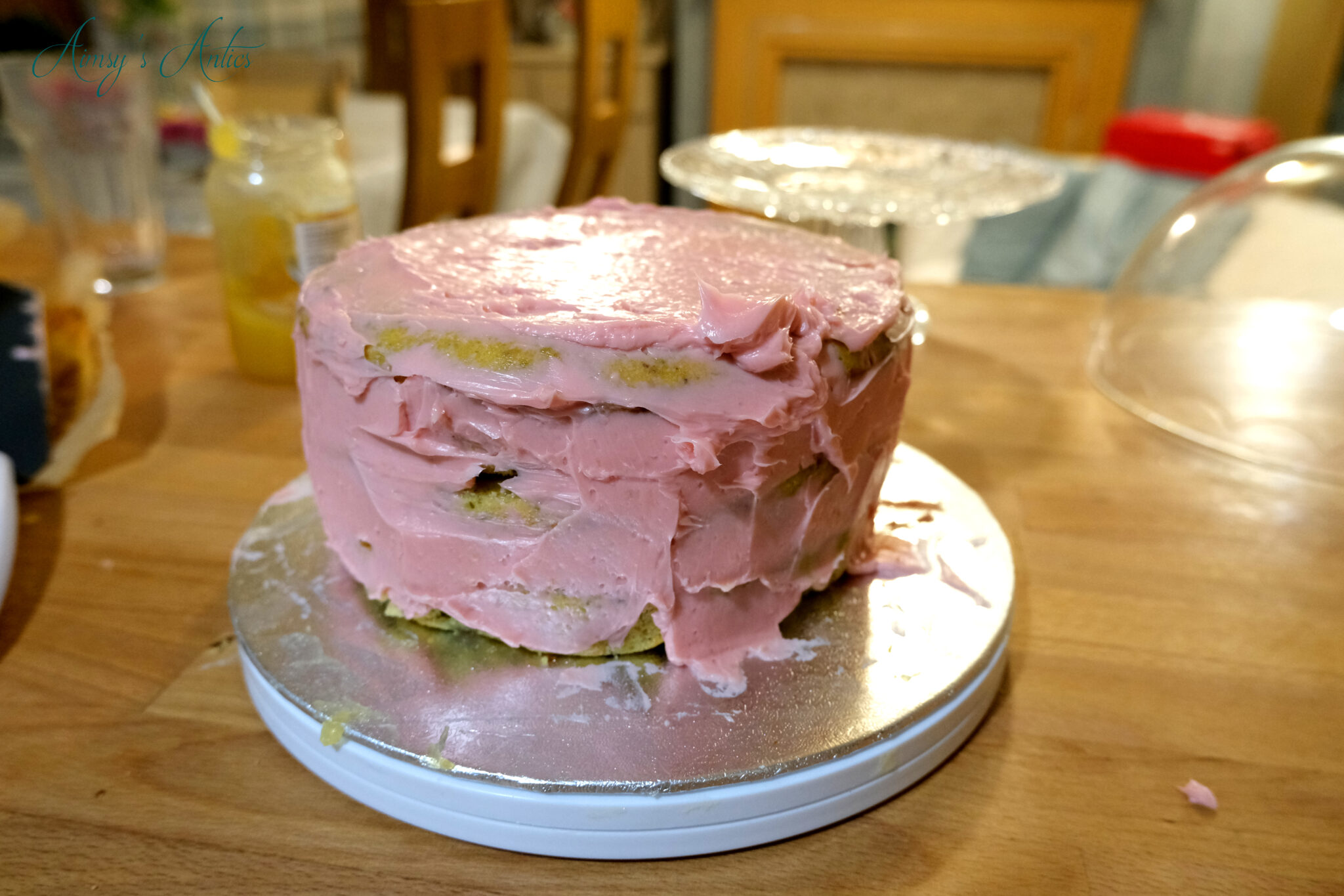 Adding the crumb coat of buttercream to the pistachio and rose cake