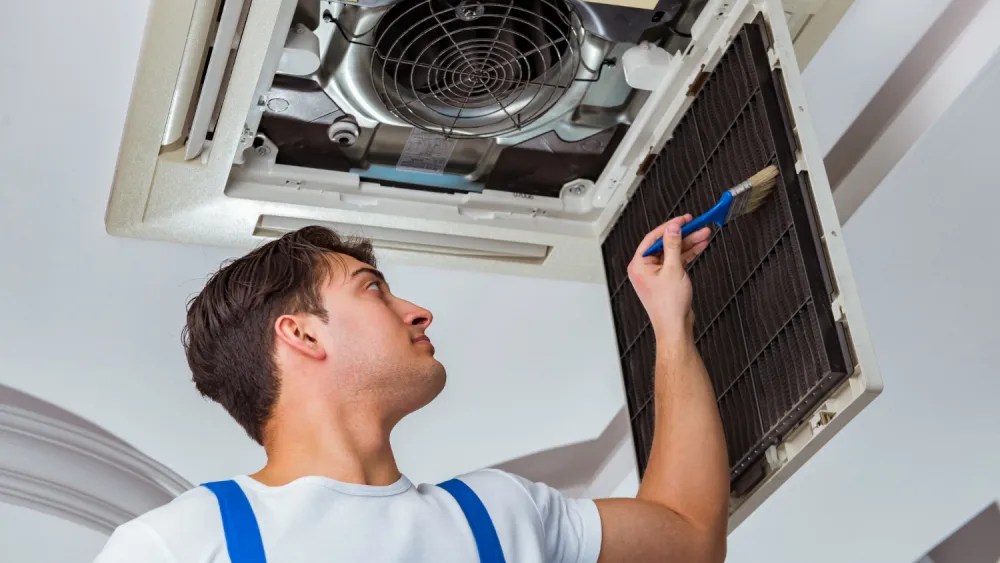 Technician cleaning a ceiling cassette aircon filter
