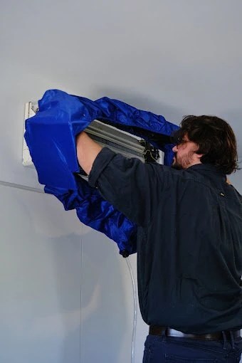 A man installing or repairing a window air conditioning unit in a wall.