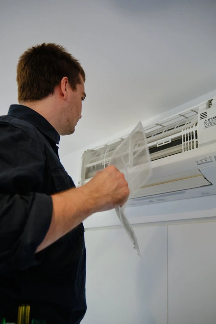 A man inspecting an air conditioning unit.