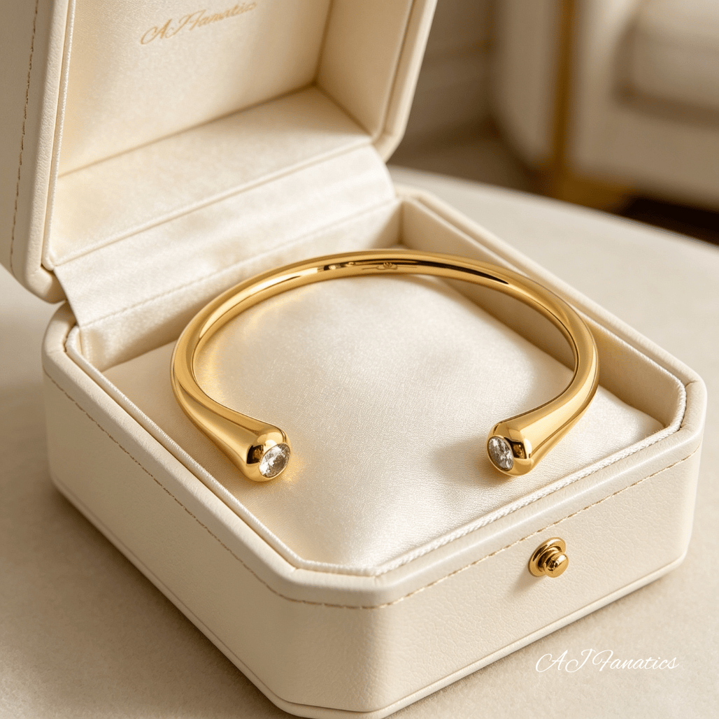 Polished gold stainless steel Fusion Spark open cuff bangle bracelet with petite cubic zirconia stones at tapered ends displayed in a jewellery box.
