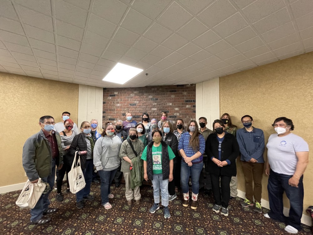 a group of people pose for a photo in the corner of a large room
