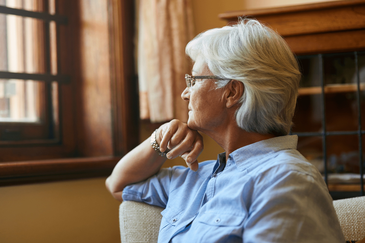 An older women looking out a window  deep in contemplation. Your Future Is Built by Your Daily Habits.