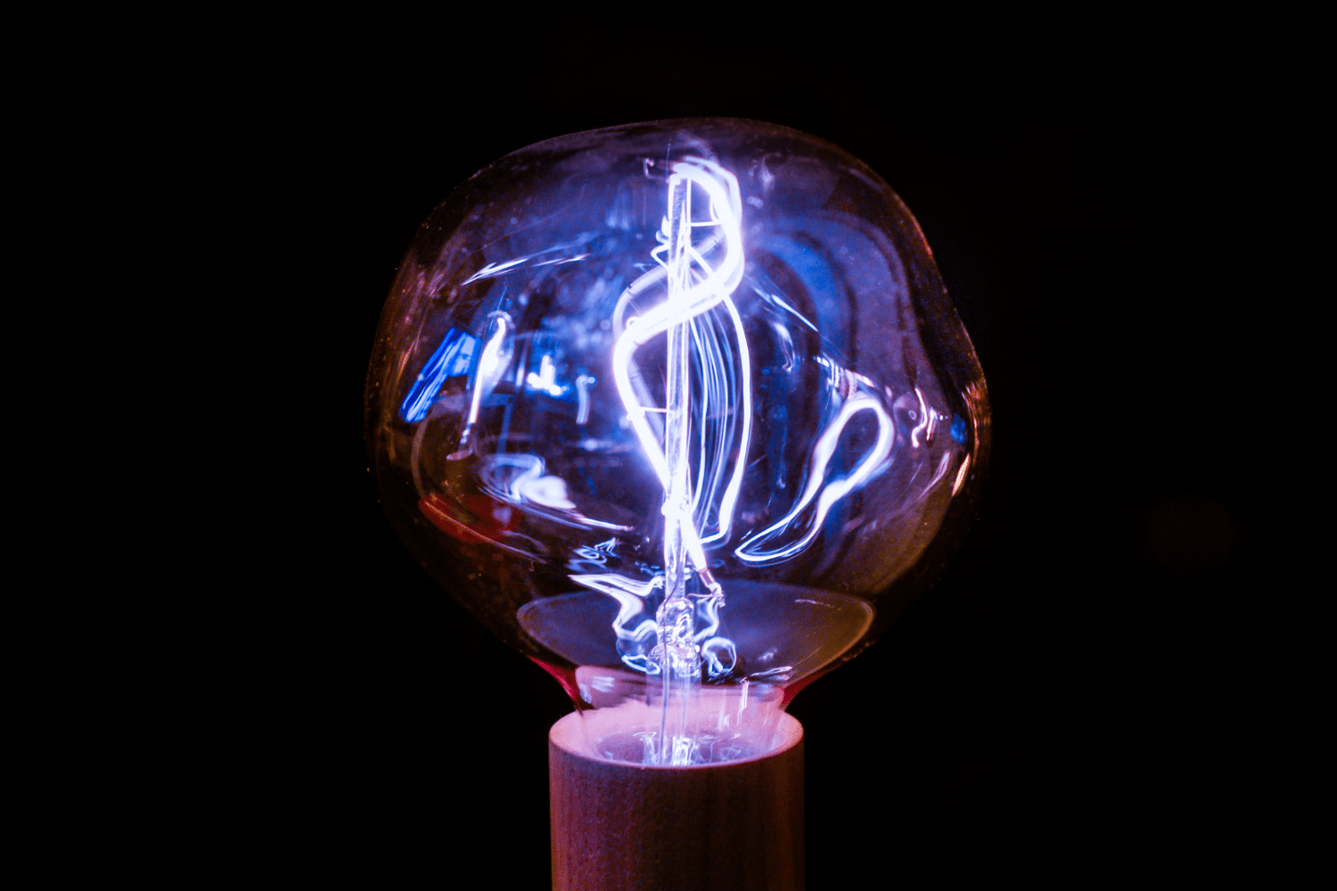 An image of a lightbulb with a purple colour on a black background.