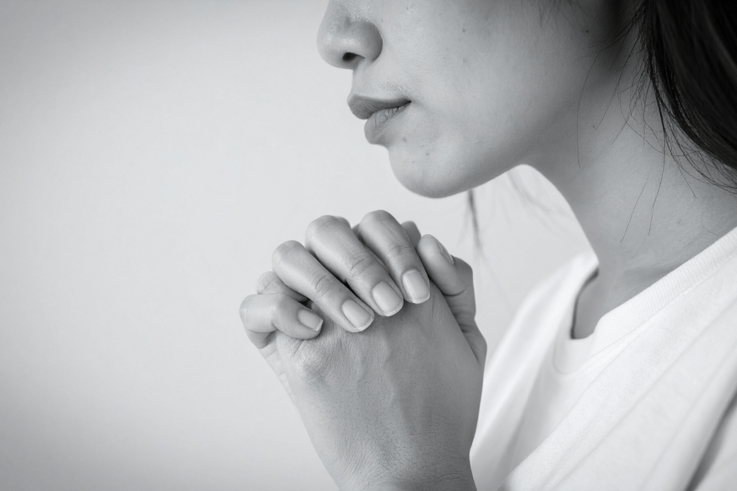 A philippian woman with her hands in a prayer gesture - Photo is a soft black and white.  