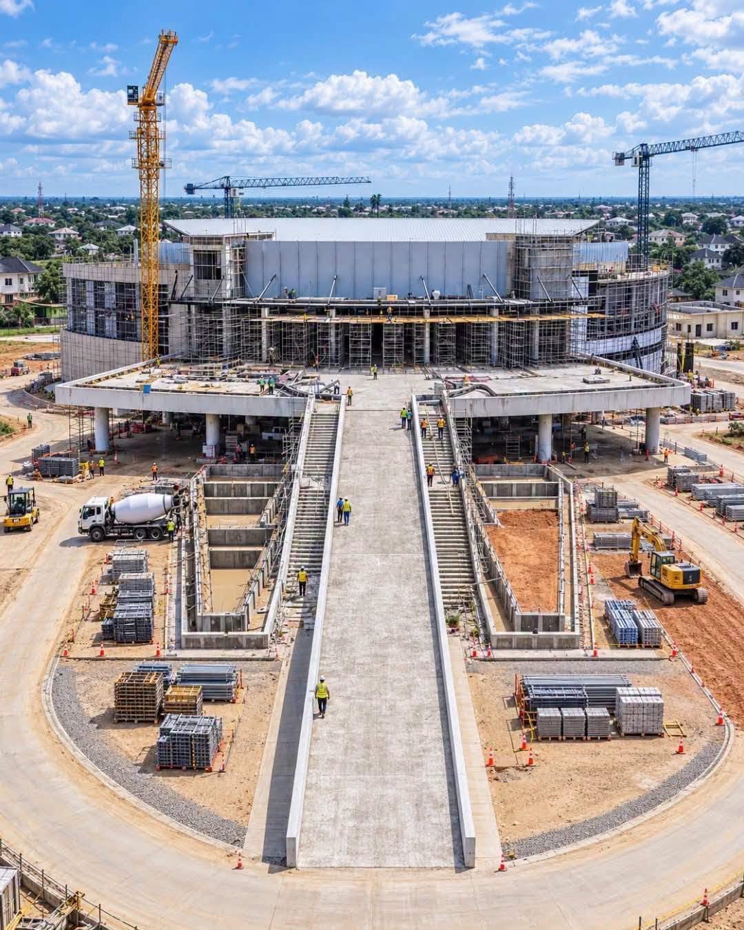 Front view of the Ibom International Convention Centre under construction, showing the entrance ramp, scaffolding and cranes.