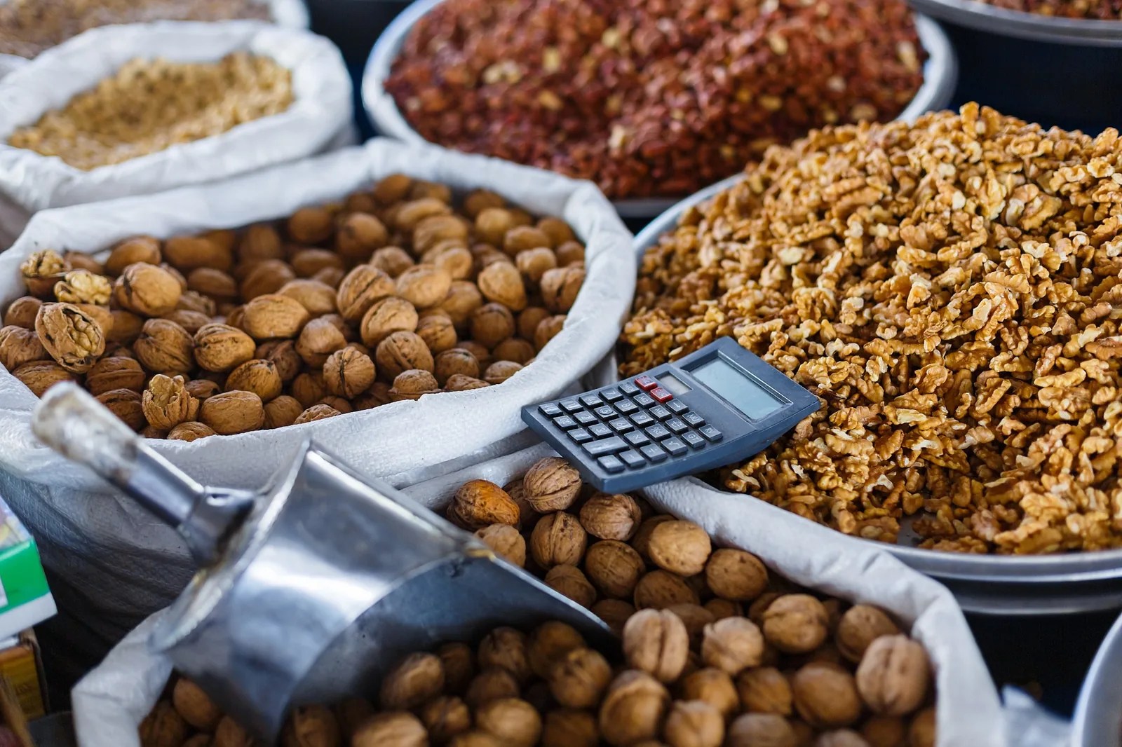 Calculator rests among open sacks of walnuts and other dry ingredients.