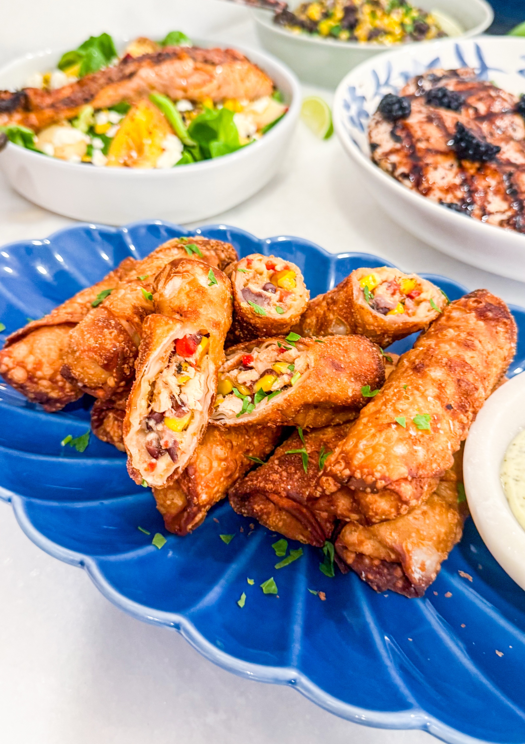 Southwest Egg Rolls - Crispy southwest egg rolls filled with chicken, cheese, black beans, corn, peppers, and served with creamy salsa verde dipping sauce