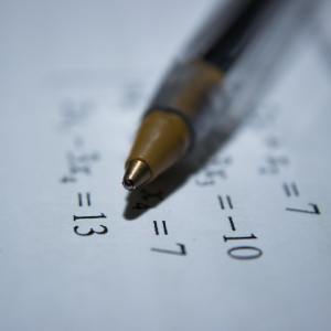 A close-up of a pen resting on a sheet with algebra equations, representing act math topics.