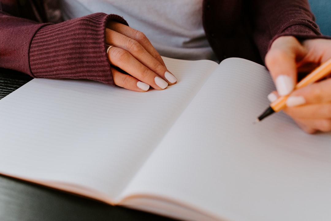 A person holding a pen over a blank notebook, ready to start memory exercises for studying.