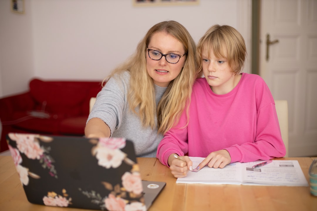 Mother assisting her child with homework at a laptop while reviewing 8th grade math standards together at home.