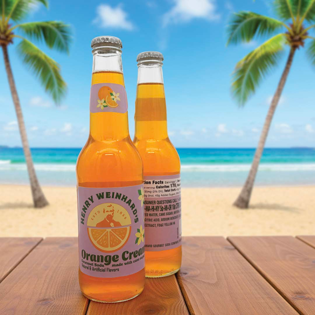 Orange cream soda bottles on a table with a beach in the background