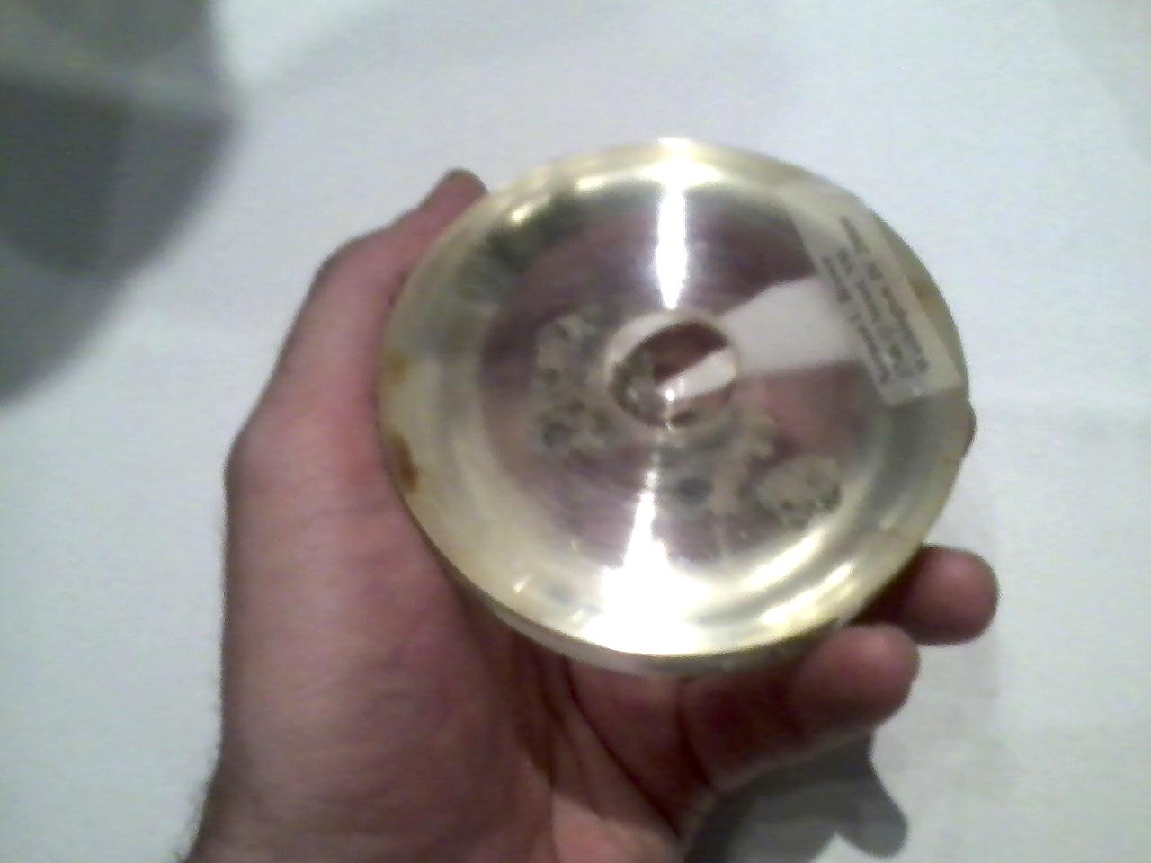 A hand holding a lucite hemisphere with a small spherical indentation in it, approximately 4 inches across