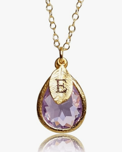 Gold necklace featuring a teardrop-shaped lavender gem and a leaf charm engraved with the letter 'E'.