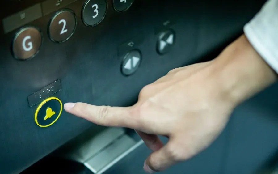 Person pressing the emergency button inside an elevator during an entrapment situation