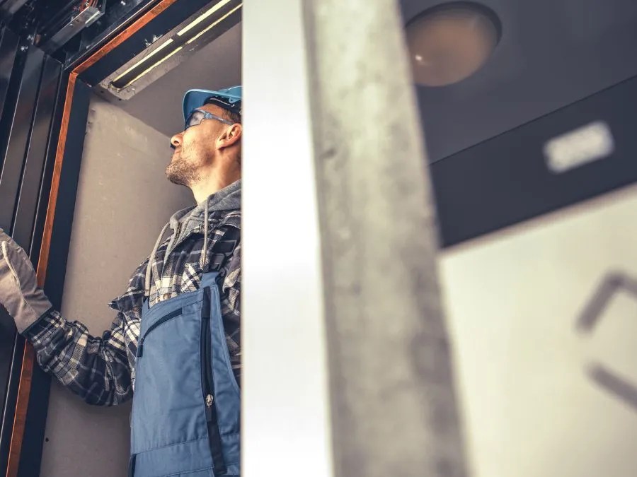 Technician inspecting elevator system comparing hydraulic and traction elevator mechanisms