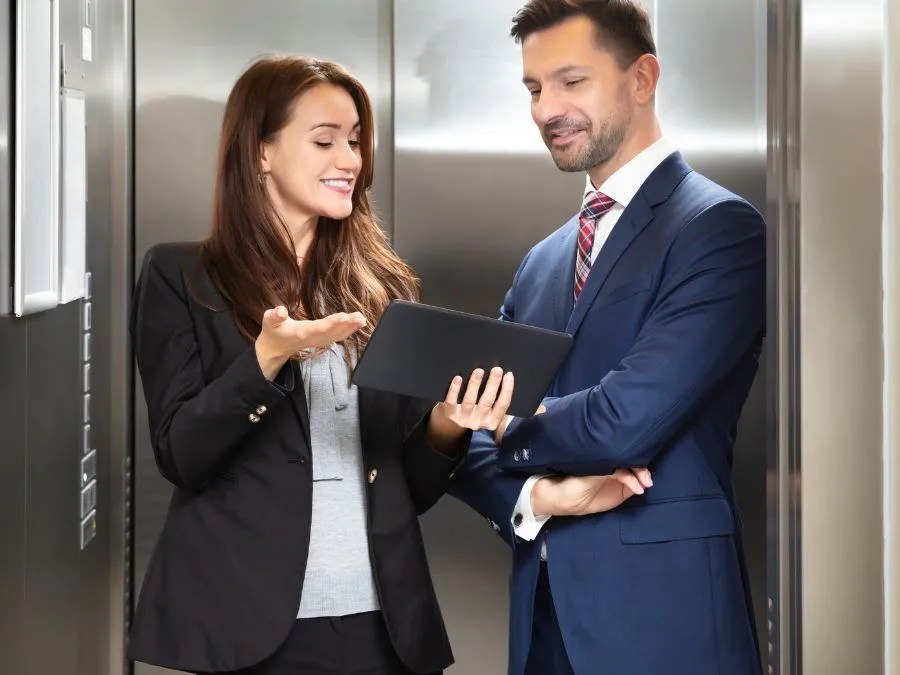 Two professionals in an elevator discussing fascinating facts about elevator history and design