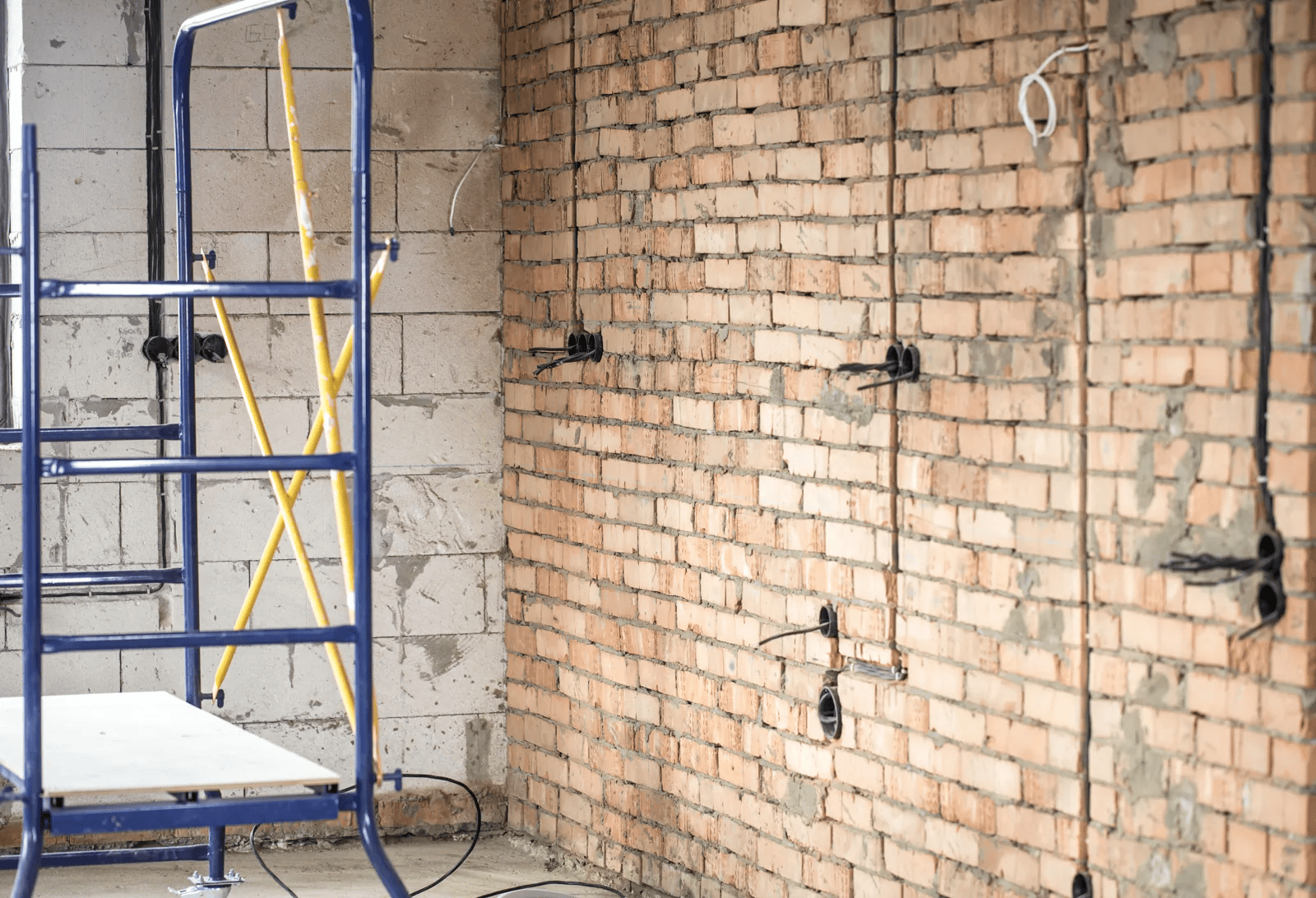 Interior reconstruction with exposed masonry, wiring and a scaffold.
