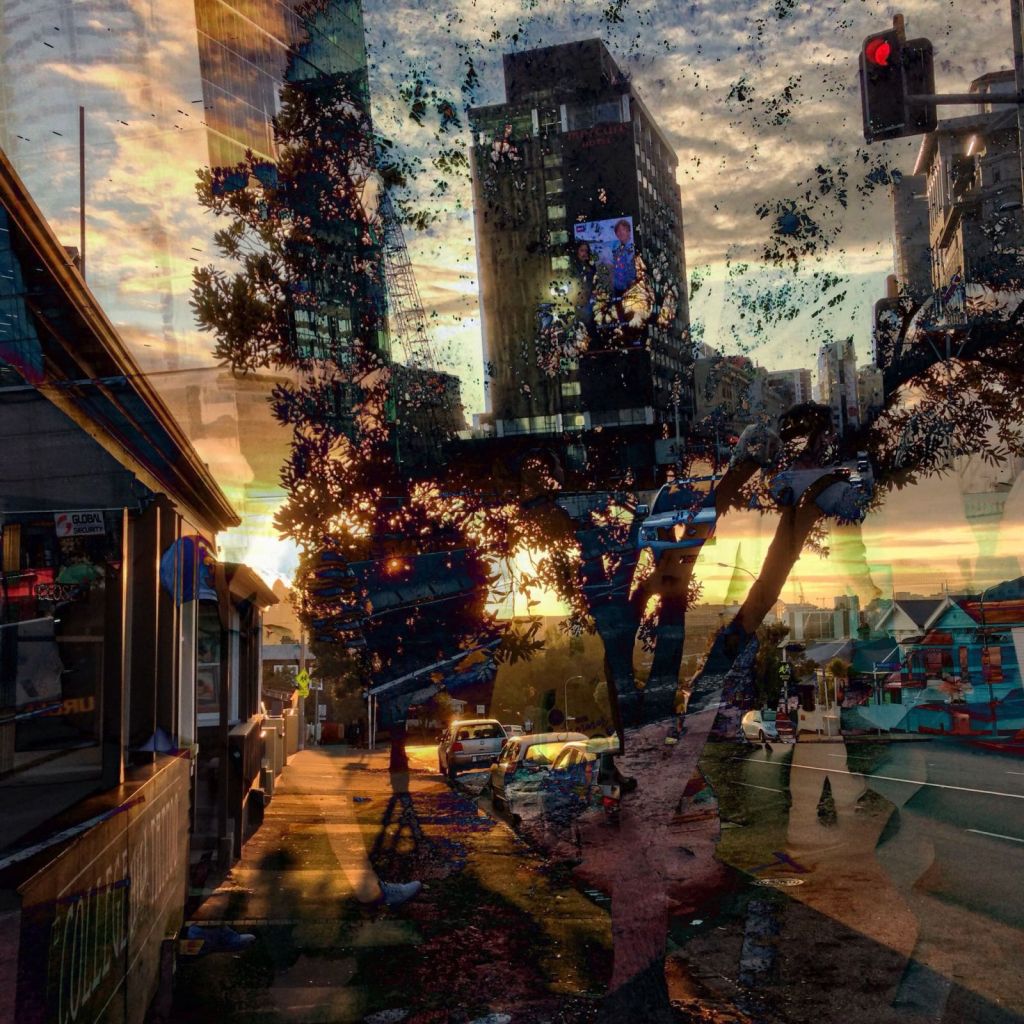 Layered colour photograph of an Auckland street at sunset, with overlapping buildings, trees, traffic and pedestrians forming a dense, swirling urban scene.