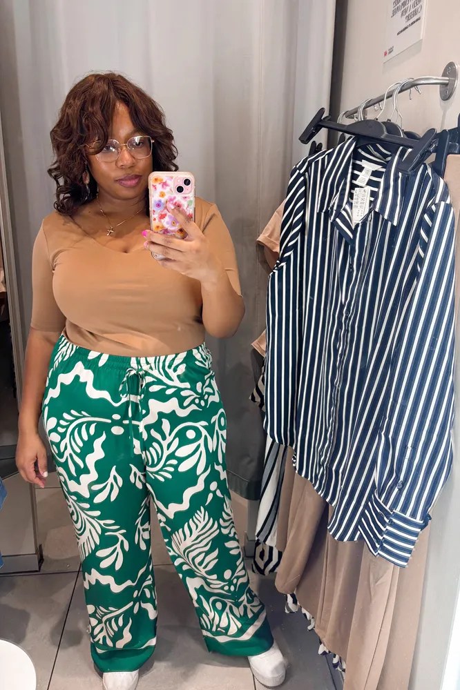 african american woman wearing a warm brown v-neck top with green tropical floral printed wide leg pants from H&M
