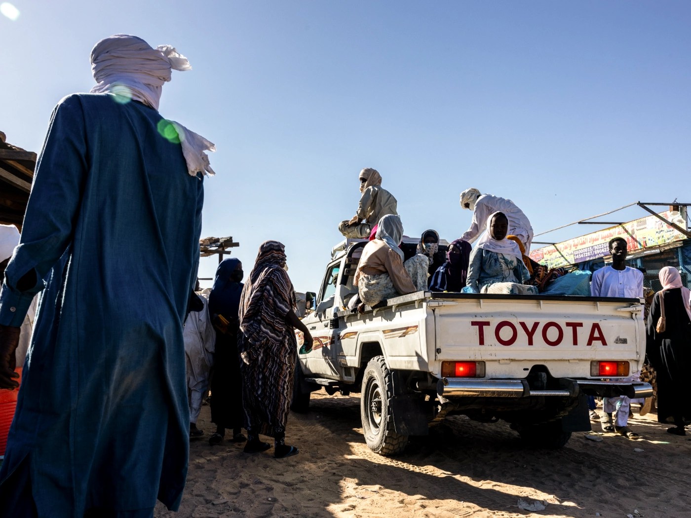 Refugiados sudaneses viajam em uma picape no mercado do campo de Oure Cassoni, no Chade, em 14 de novembro de 2025
