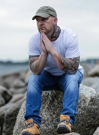 man sitting on large rock staring into the distance