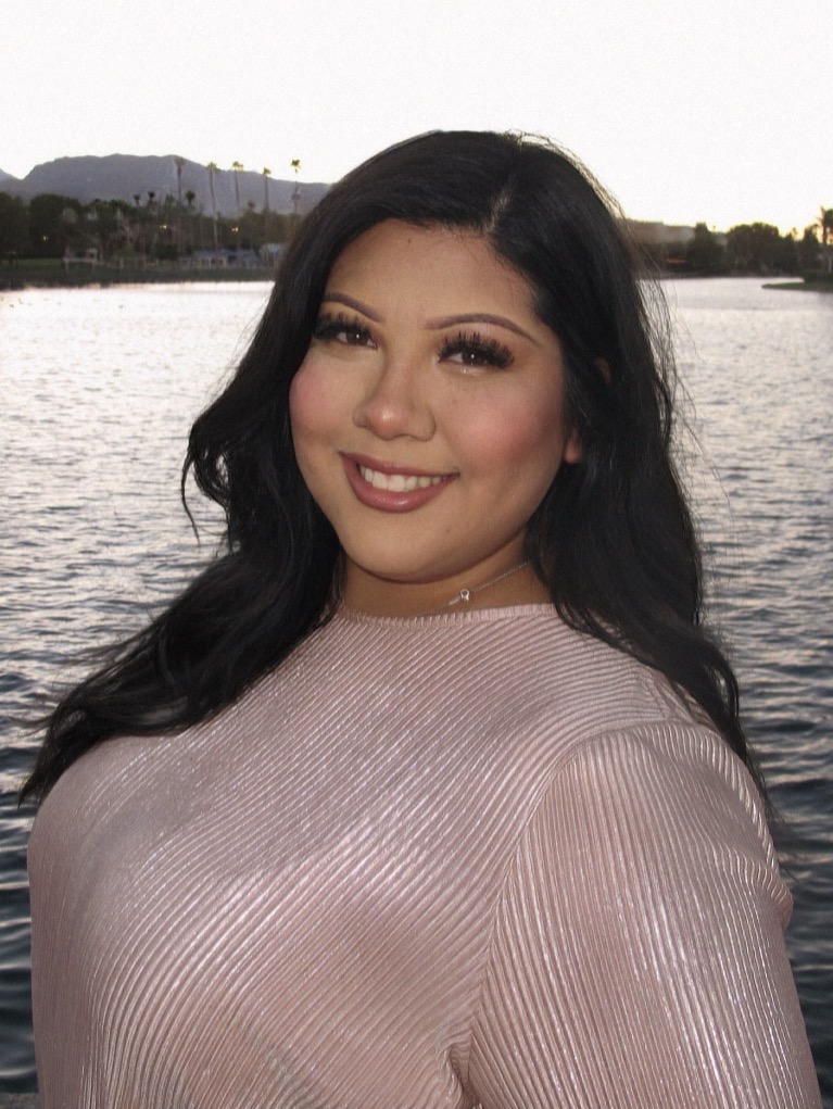 Smiling Clinical Social Worker Ariana Camarena, LMSW, CSW-I, standing near a lake with mountains in the background