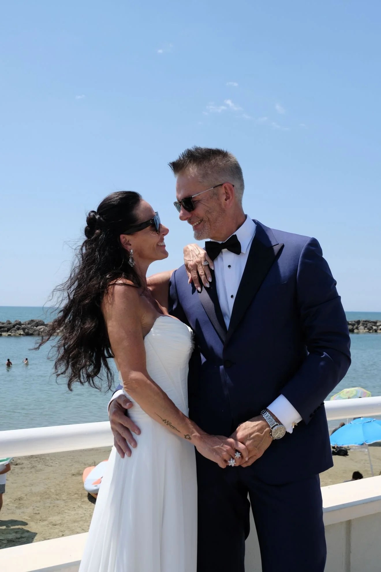Bride and groom posing together by the waterfront on their wedding day