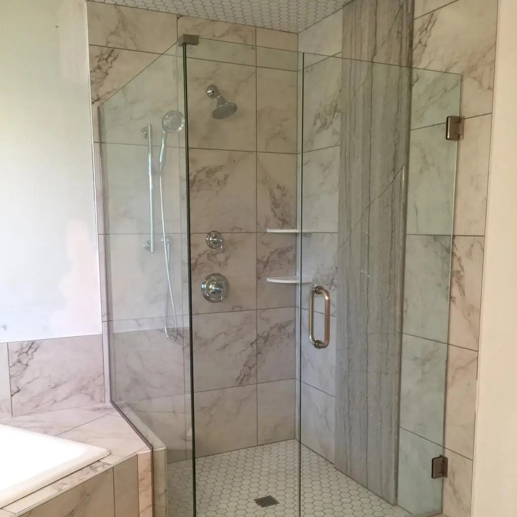 A stand up shower with porcelain tile and glass