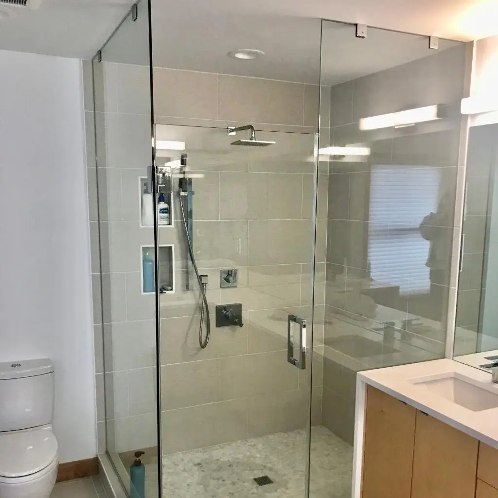 A walk in shower with a handheld shower valve and subway tile