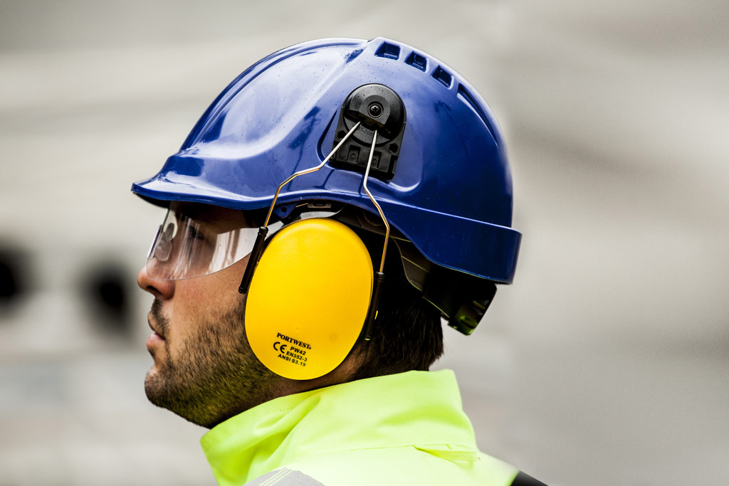 Travailleur avec toutes les protection de la tête : casque de chantier, coquilles anti bruit, lunette de protection