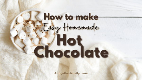 hot to make easy homemade hot chocolate white mug of hot cocoa with mini marshmallows with a cozy white knit blanket