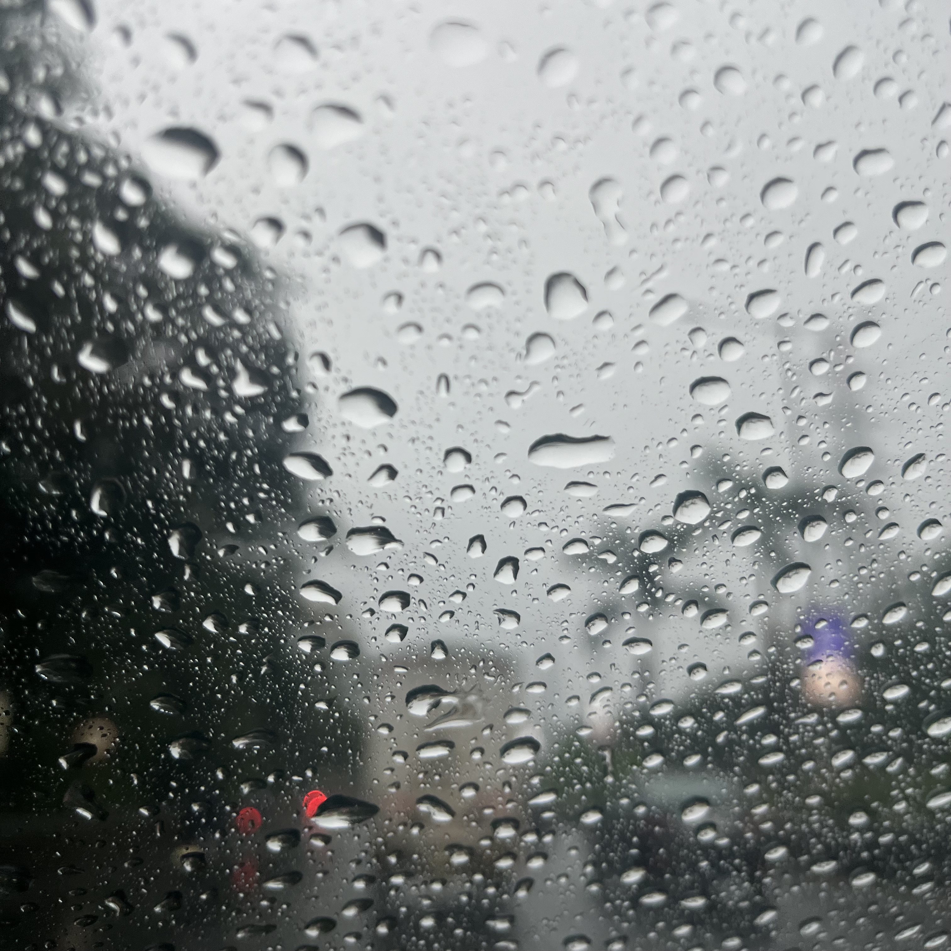 Drops on water on a glass window, grey skies in the background.