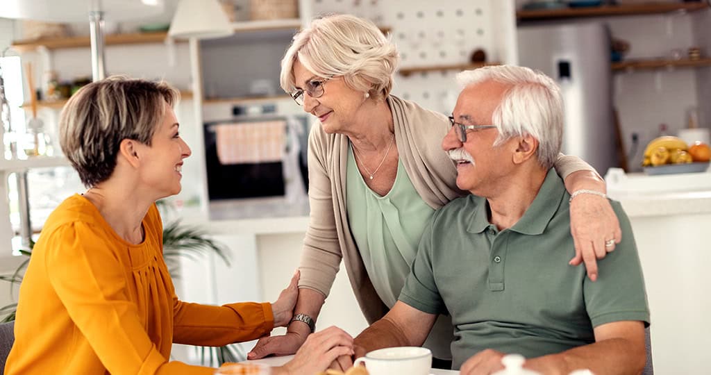 Adult woman talking with her aging parents at the breakfast table