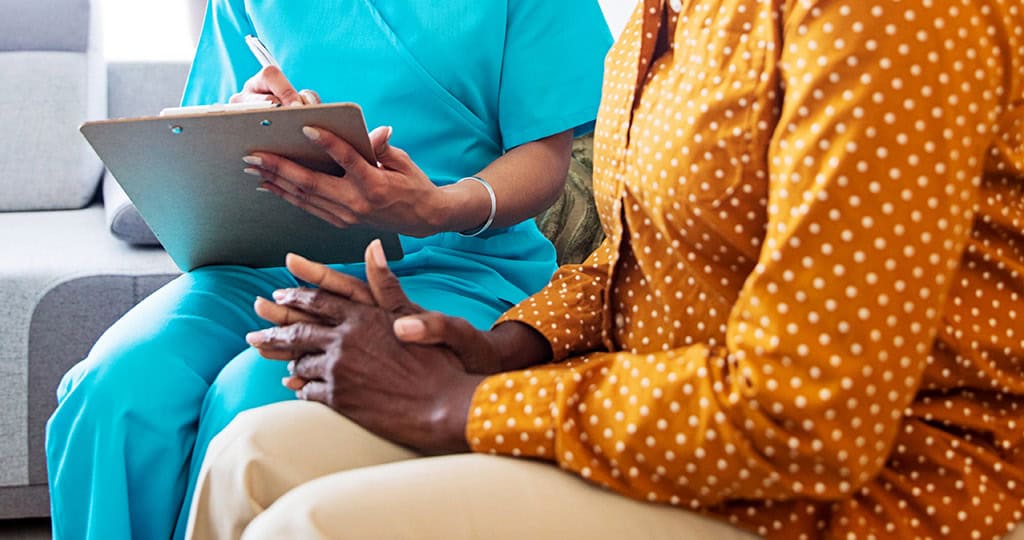 Caregiver taking notes while talking with senior woman
