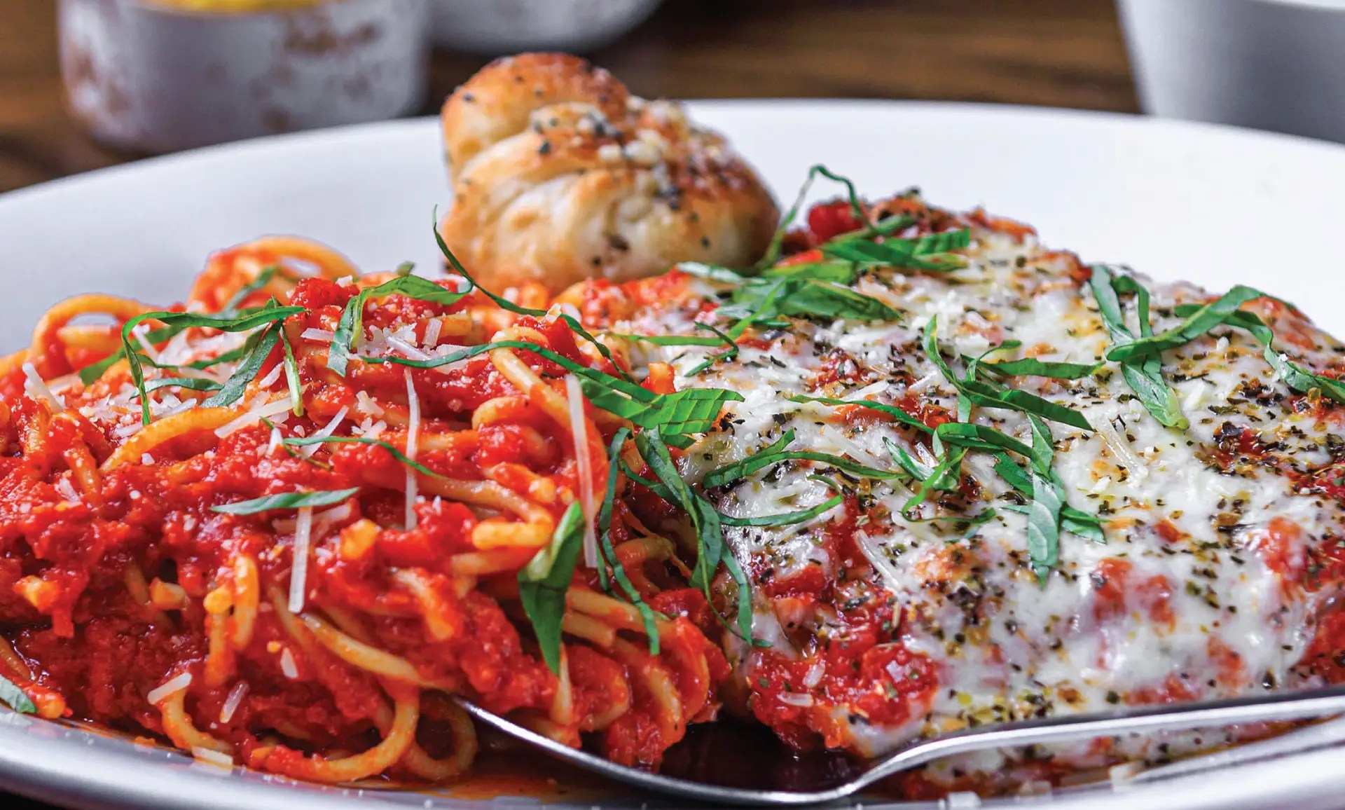 Chicken Parmesan from Amici - beautifully plated. Italian breaded fried chicken baked with ricotta, fresh basil, Amici marinara and provolone served with spaghetti.